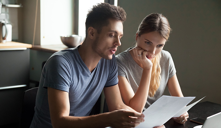 Serious confused young couple checking bills, bank, loan documents with using laptop, large credit card bills, reading bad news, having debt financial problem concept