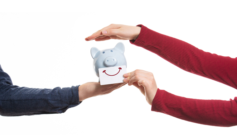 Close up of man and woman hands protecting a piggy bank with smile sticker isolated on white. Business partnership and collaboration. Concept for protecting your assets, financial help and insurance.
