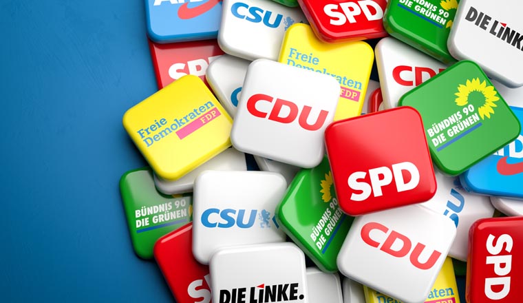 Logos of the biggest German political parties (CDU CSU, SPD, Die Grünen, FDP, Die Linke, AfD) running for the Bundestag election on a heap on a table. Copy space. 