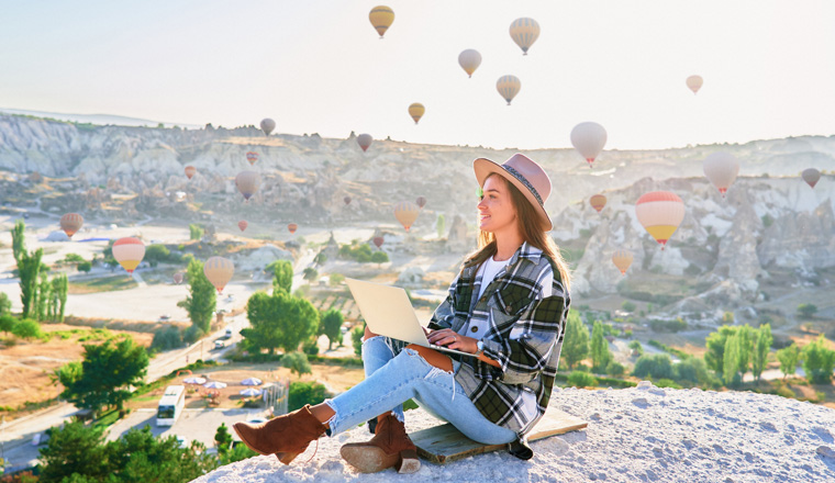 Inspired happy smiling travel blogger girl working remotely and enjoying air balloons landscape