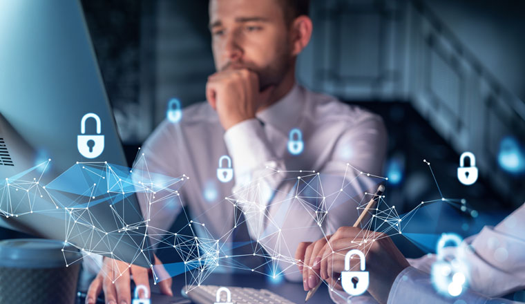 Two colleagues working together to protect clients confidential information and cyber security. IT hologram padlock icons modern office background at night time
