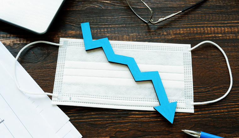 Medical mask and down arrow as symbol of decrease of economy or number of cases per covid-19.