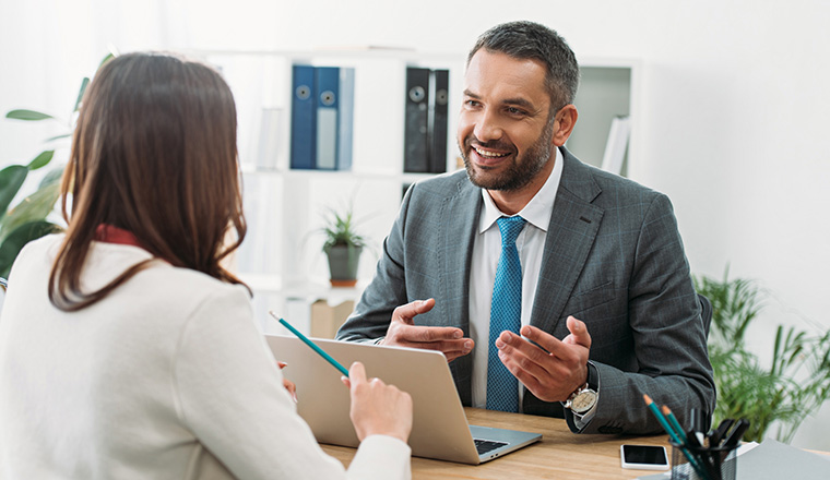 selective focus of advisor sitting at table with laptop and woman in office