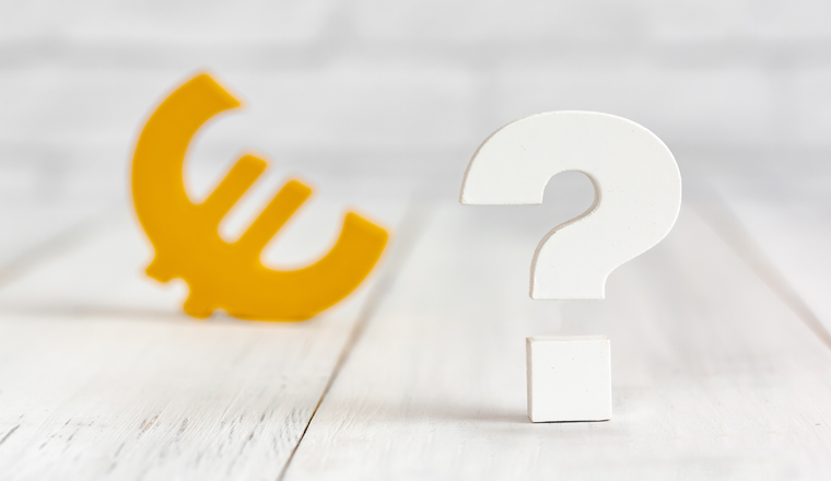 Question mark with euro sign on white wood table over white brick background with copy space.