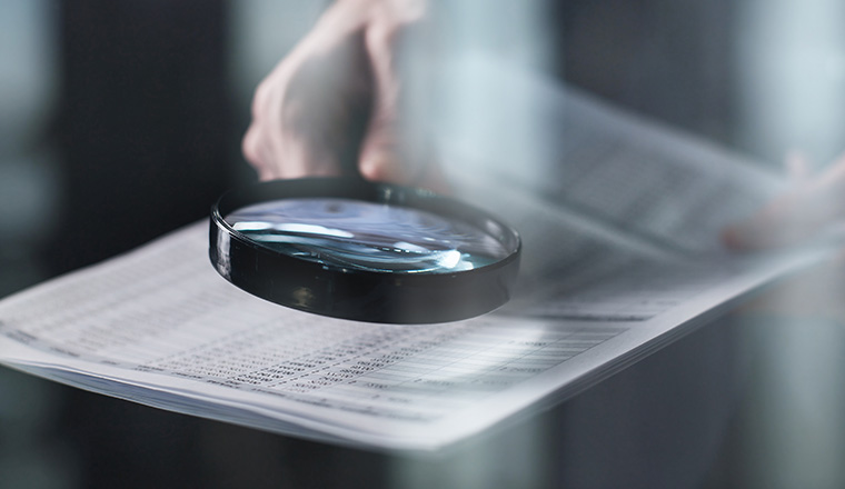 Young businessman looking to a contract through a magnifying glass