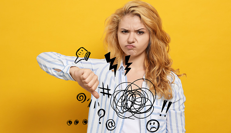 Complaint. Dissatisfied young woman showing thumb down gesture on yellow background, Different illustrations near her hand