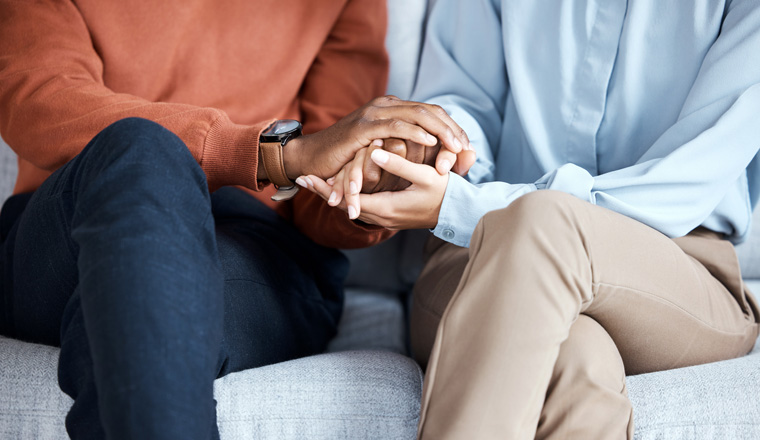 Holding hands, couple and psychology help on sofa for support, solidarity or love for growth in relationship. Black people, couch or helping hand at therapy consultation for problem, fight or anxiety.