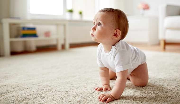 childhood, babyhood and people concept - little baby boy or girl crawling on floor at home