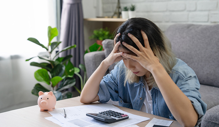 Young Asian woman looking at credit card invoice in her hands and worry about cash on bills payday. Business financial concept