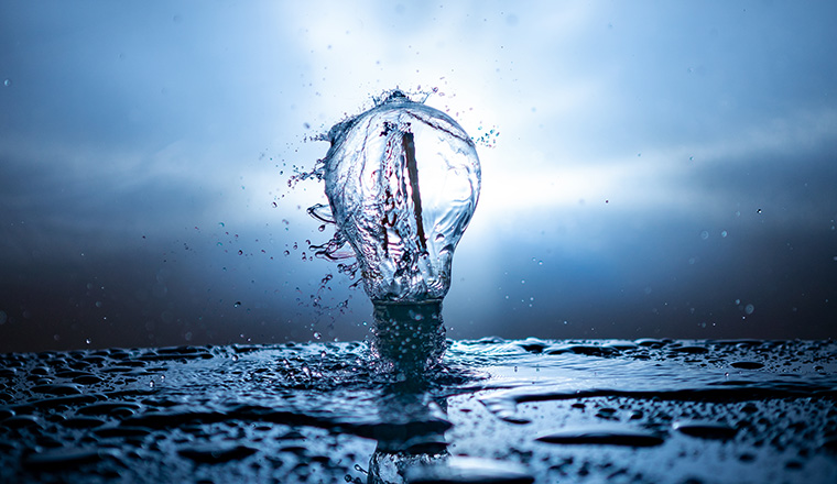 A light bulb with water splashes on a blue background - energy concept