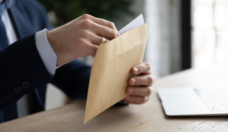 Crop close up of male employee or CEO sit at table open envelope with postal letter or mail. Caucasian businessman consider receive post paper correspondence or document message at workplace.