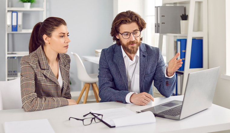 Woman consulting with insurance agent, bank manager, financial advisor, realtor or loan broker. Specialist meeting with client in office, talking about deal and showing something on laptop computer