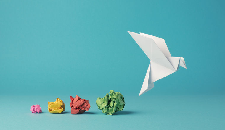 Colorful crumpled paper balls with an origami paper dove, peace, freedom, diversity or opportunity concept on a blue background