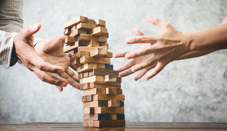 Business man and woman playing wood jenga game blocks in office studio.