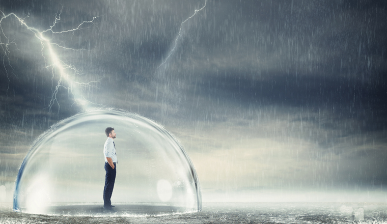 Businessman safely inside a sphere during a storm . Protection from the crisis concept