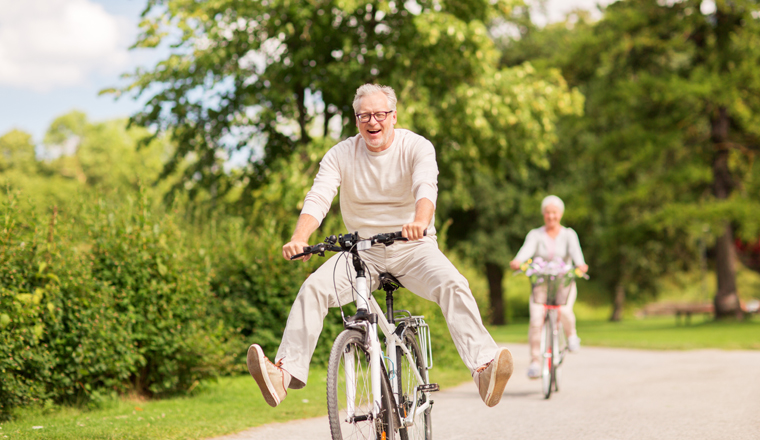 active old age, people and lifestyle concept - happy senior couple riding bicycles at summer park