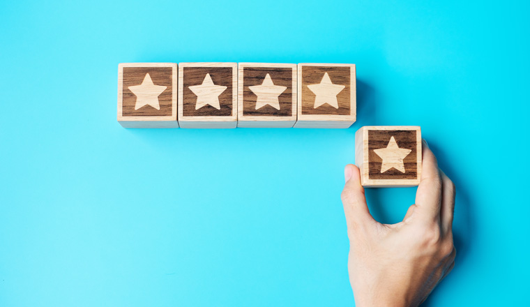 hand holding Star block on blue background. Customer choose rating for user reviews. Service rating, ranking, customer review, satisfaction, evaluation and feedback concept