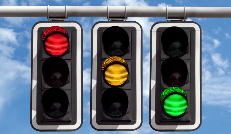 Three traffic lights against blue sky background