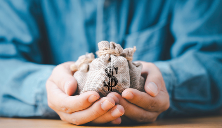 Businessman holding money bag with USD dollar sign for give dividend return profit from investment funding and stock market , Financial and accounting concept.