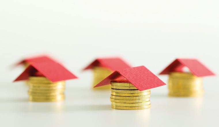 Houses made from lot of coins and a red color paper roof