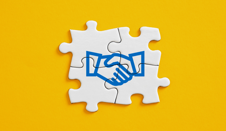Business agreement or consensus building of different parties. Strategic alliance, teamwork or business partnership concept. Jigsaw puzzle pieces with handshake icon.