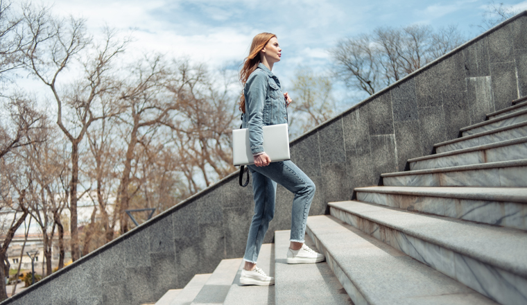 Young woman student climbs the stairs up