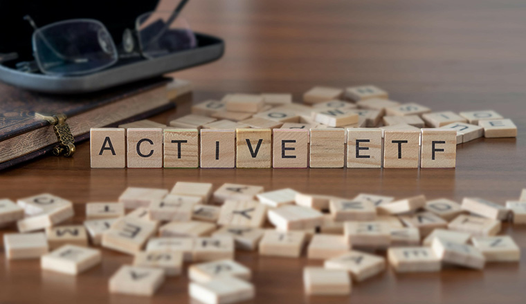 active etf word or concept represented by wooden letter tiles on a wooden table with glasses and a book