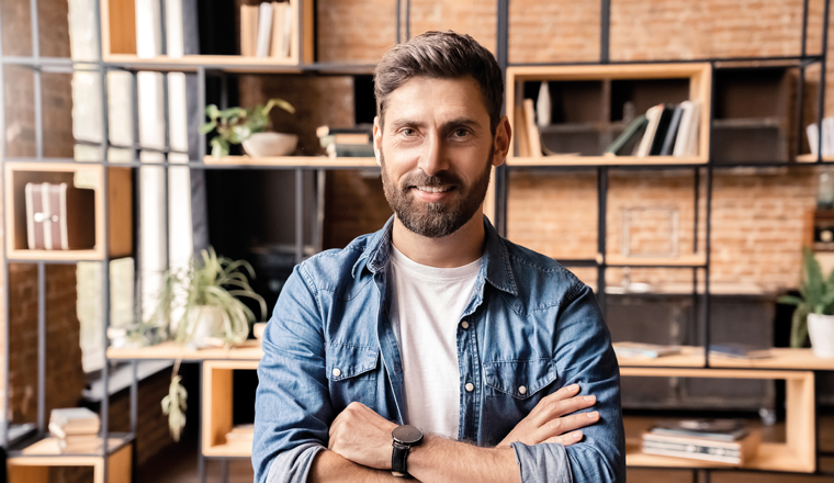 Caucasian businessman freelancer standing with arms crossed on chest looking at camera show confidence headshot portrait. Calm smiling handsome employee worker on freelance over home office interior