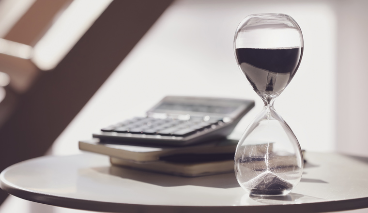 Hourglass, calculator and notebooks on table