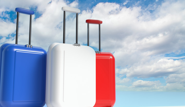 Travel suitcases in the colors of the flag of France against the sky with clouds with empty space for text. 3d illustration on the theme of business trips.
