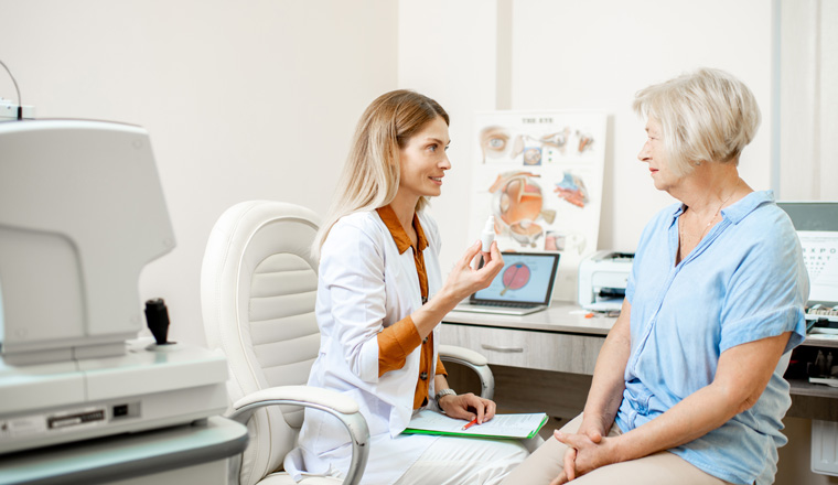 Senior woman patient talking with female ophthalmologist during a medical consultation at the ophthalmologic office. Doctor offering eye medcine for a patient