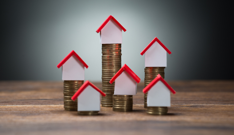 House models on stacked coins at wooden table