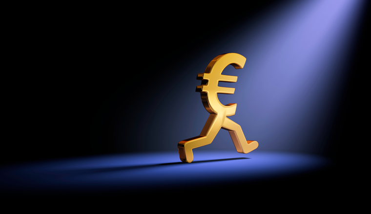 A gold Euro symbol in the dark is caught in a bright spot light as it runs away. 