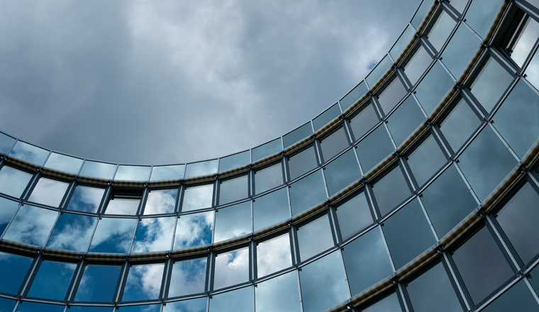 Gebäude mit Fassade aus Glas und dunklen Wolken am Himmel