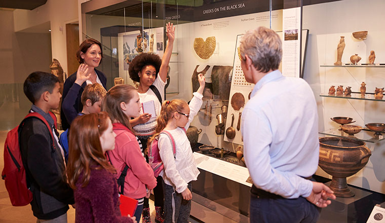 Students Looking At Artifacts In Case On Trip To Museum