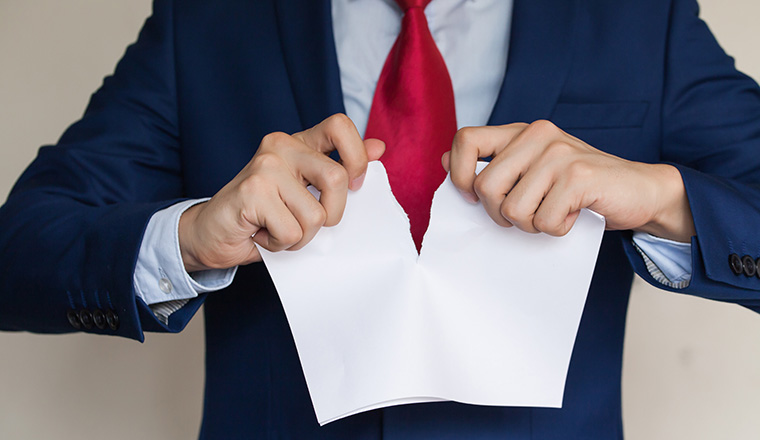 Businessman tearing blank paper apart on white background