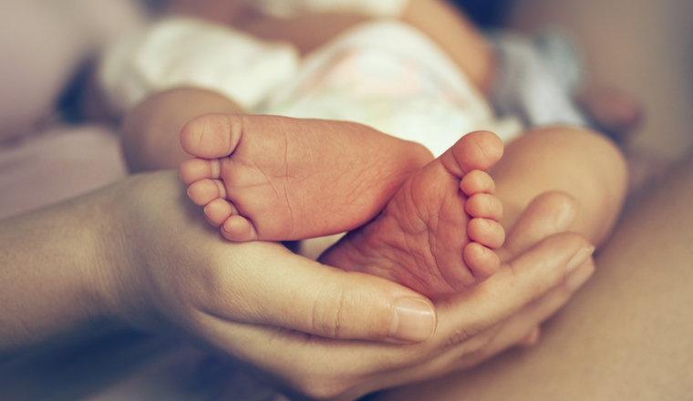 Feet of newborn baby on mother's palm