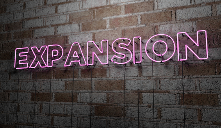 EXPANSION - Glowing Neon Sign on stonework wall - 3D rendered royalty free stock illustration.  Can be used for online banner ads and direct mailers.
