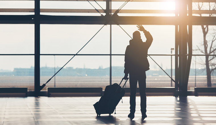 Saying goodbye at the airport. Silhouette of the traveler waves his hand.