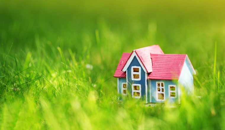 red wooden house model on the grass in garden