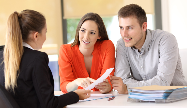 Two happy customers solving doubts about a contract with the saleswoman at office