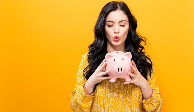 Young woman with a piggy bank on a yellow background