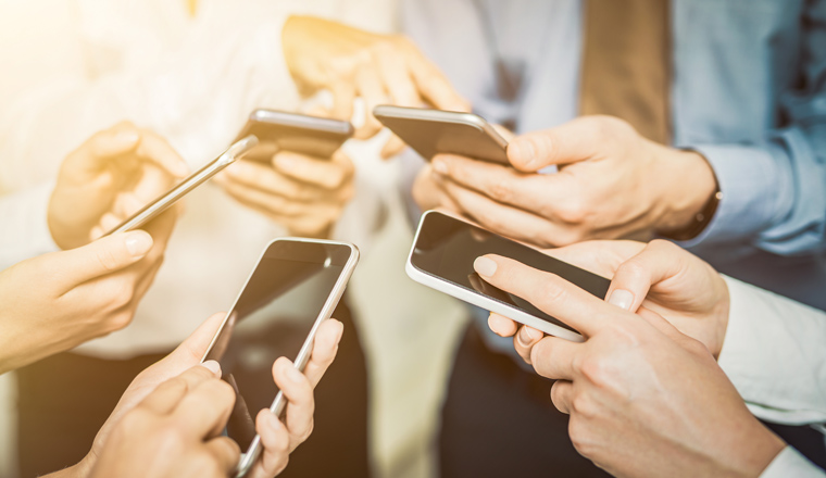 Group of young hipsters holding phone in hands. Friends having fun together with smartphones.