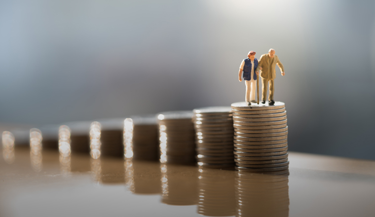 Concept of retirement planning. Miniature people: Old couple figure standing on top of coin stack.