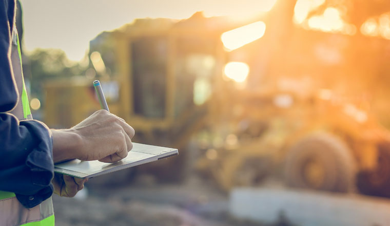 Asian engineer with hardhat using  tablet pc computer inspecting and working at construction site