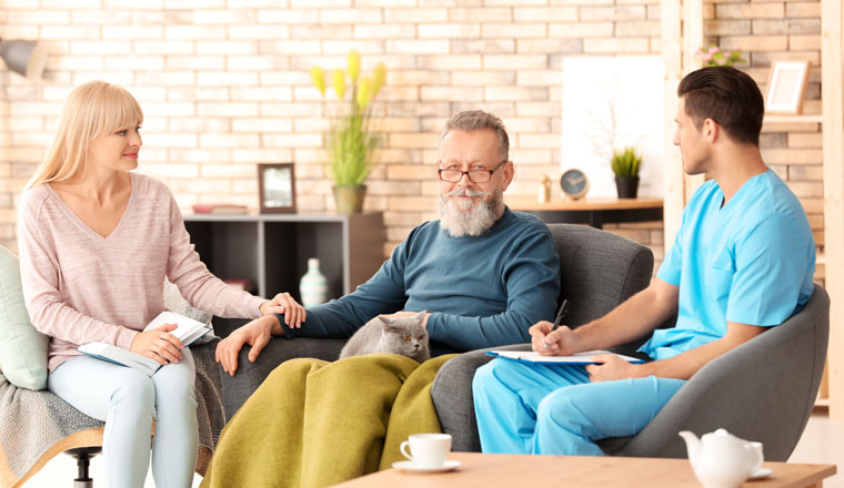 Caregiver with senior man and his daughter at home