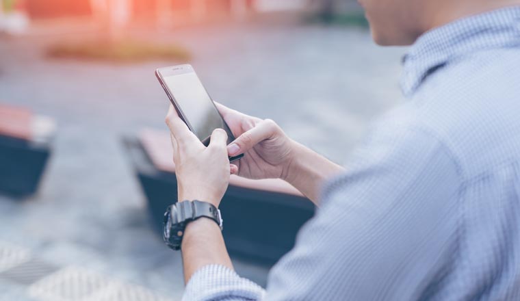 Young asian handsome businessman smilling and using his smartphone. Portrait of asian business man happy and using smart phone in outdoor.