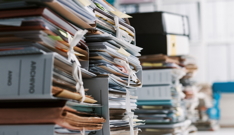 Stacks of paperwork and files in the office: work overload, files management and administration concept
