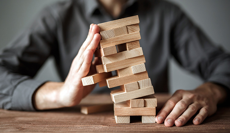 Businessman holds the model of business, made from wood blocks. Alternative risk concept, business plan and business strategy. Insurance concept.