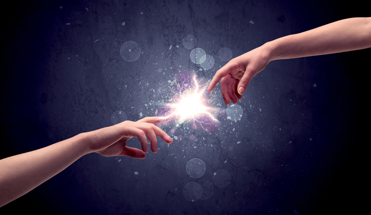 Two male hands reaching towards each other, almost touching with fingers, lighting spark in galaxy background concept